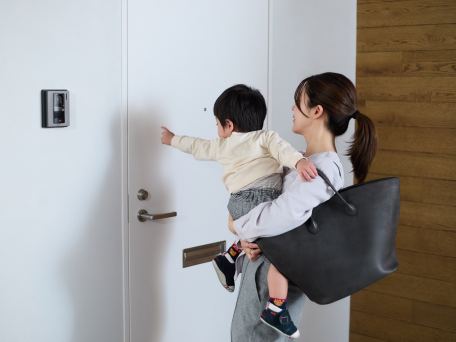 子どもを抱っこしたまま玄関ドアの前に立つ様子
